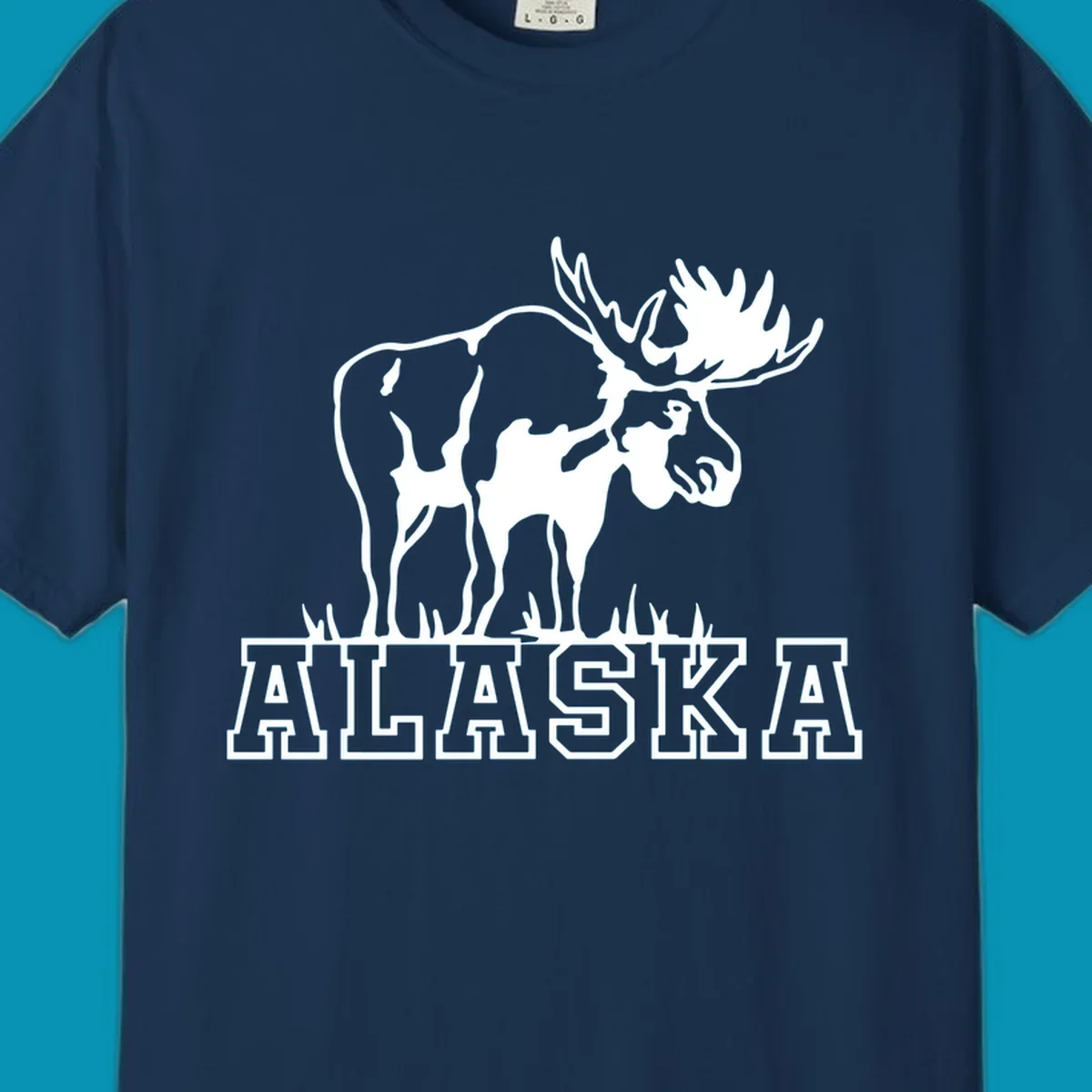 White silhouette of a majestic moose with large antlers standing with grass below and ALASKA text, moose-alaska-silhouette design