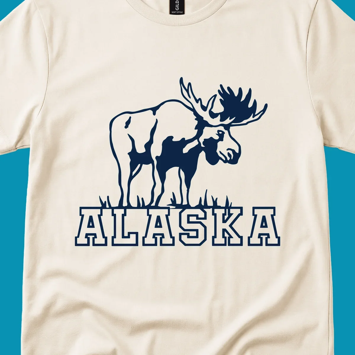 White silhouette of a majestic moose with large antlers standing with grass below and ALASKA text, moose-alaska-silhouette design
