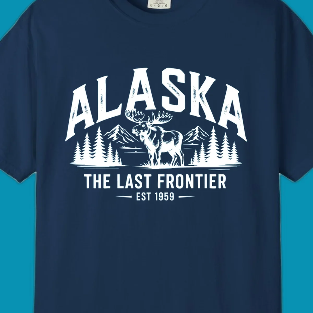 A white alaska-moose-frontier-scenic graphic showing a moose standing in front of mountains and pine trees.