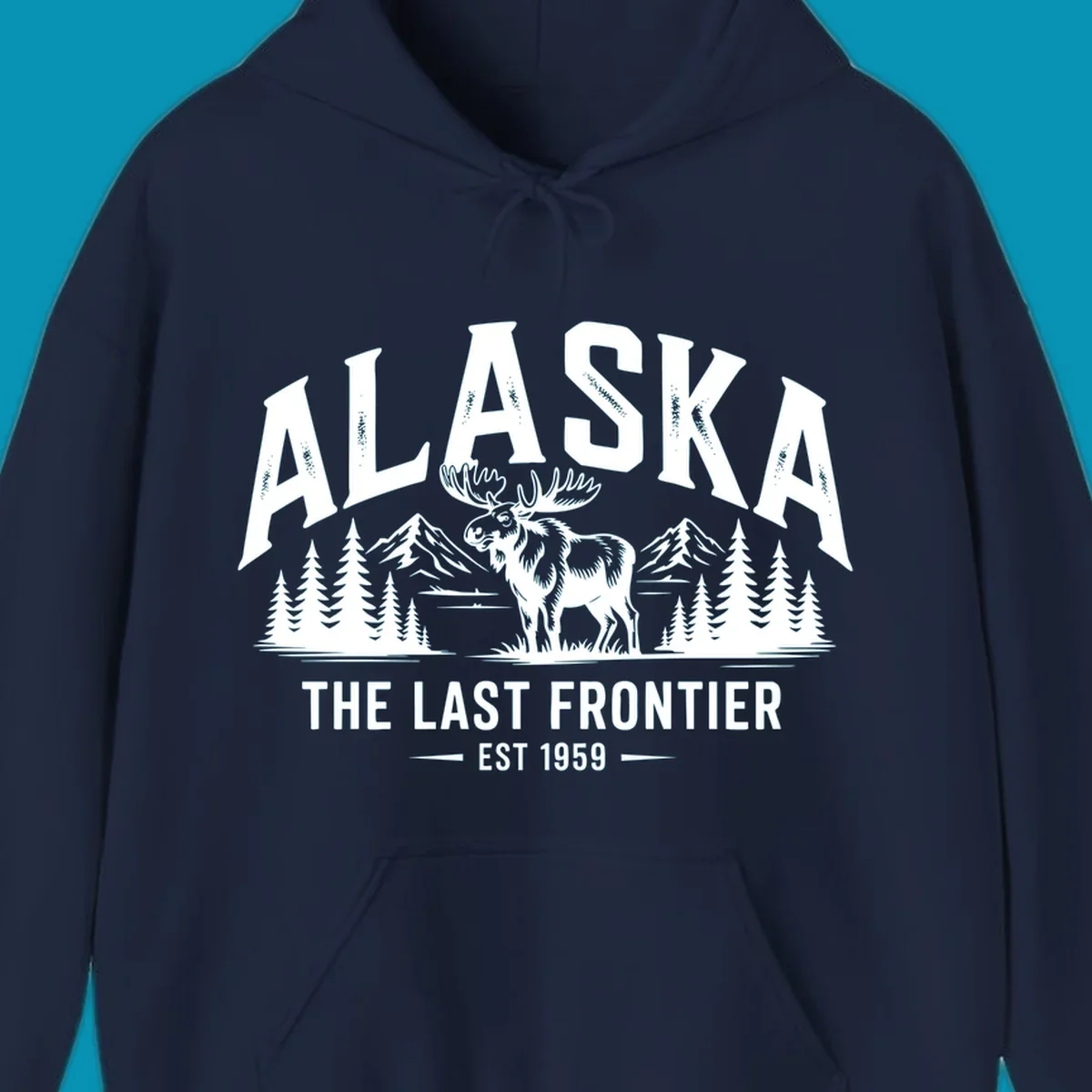 A white alaska-moose-frontier-scenic graphic showing a moose standing in front of mountains and pine trees.