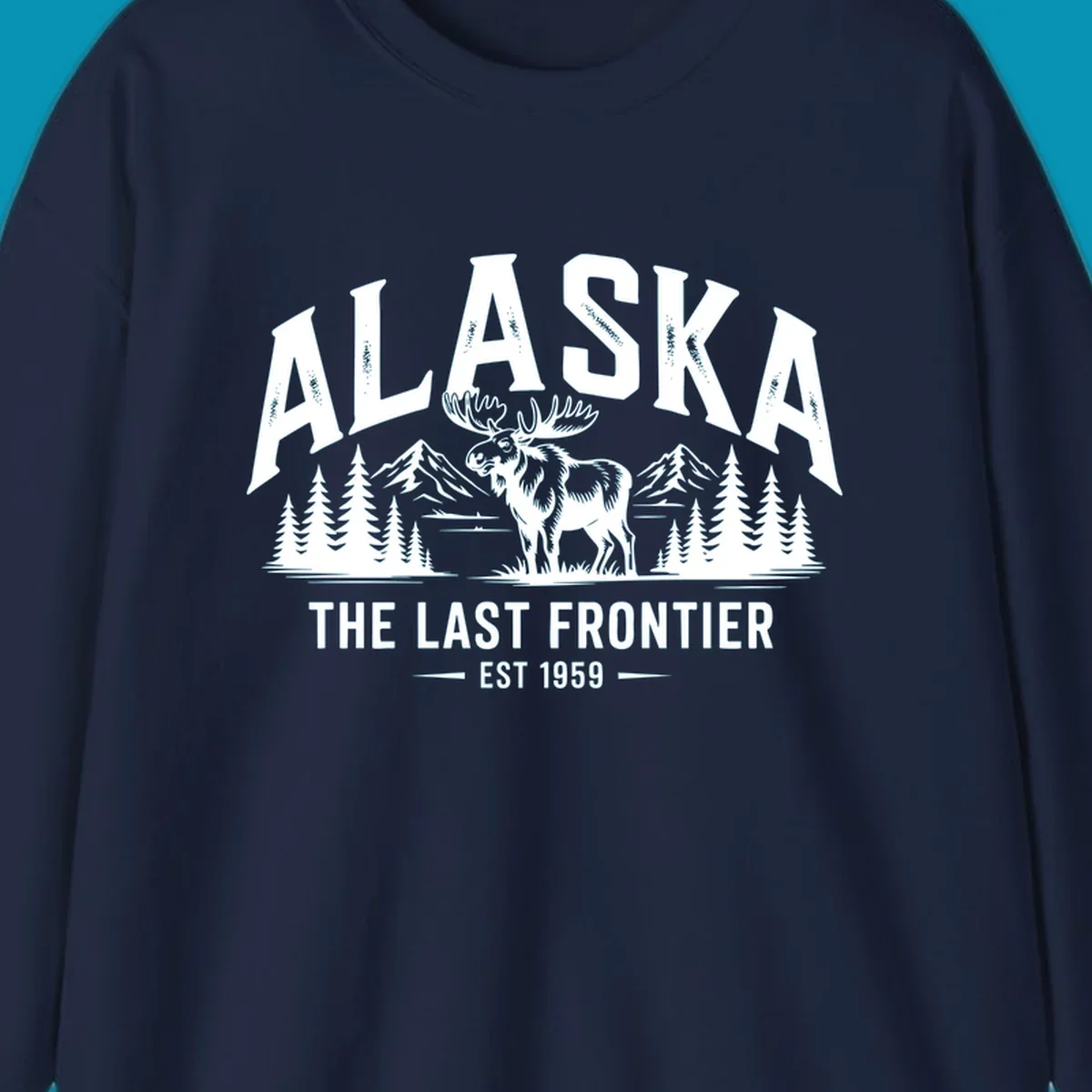 A white alaska-moose-frontier-scenic graphic showing a moose standing in front of mountains and pine trees.