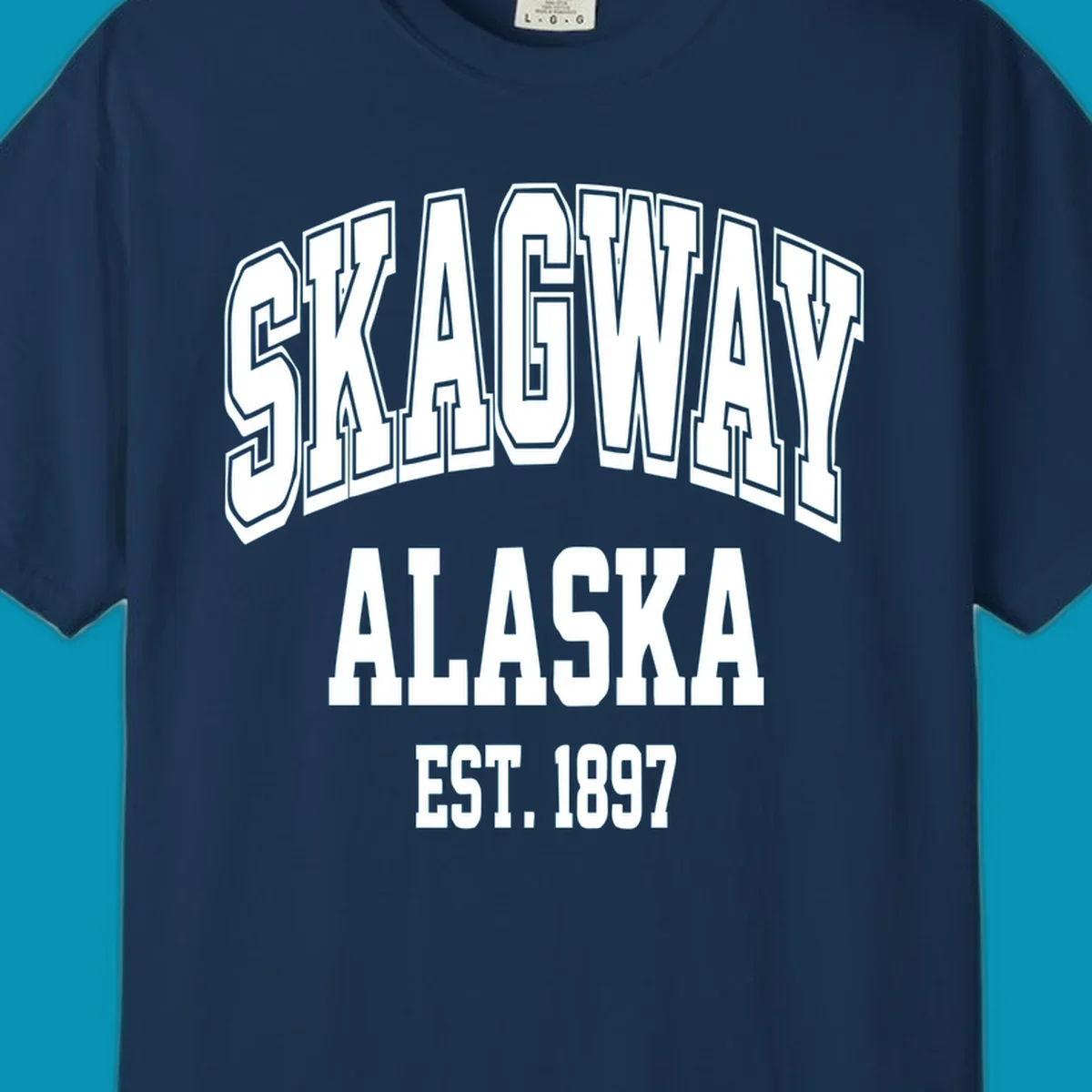Vintage-style badge with bold outlined text reading Skagway Alaska Est. 1897 with decorative arrow accents on gray background.