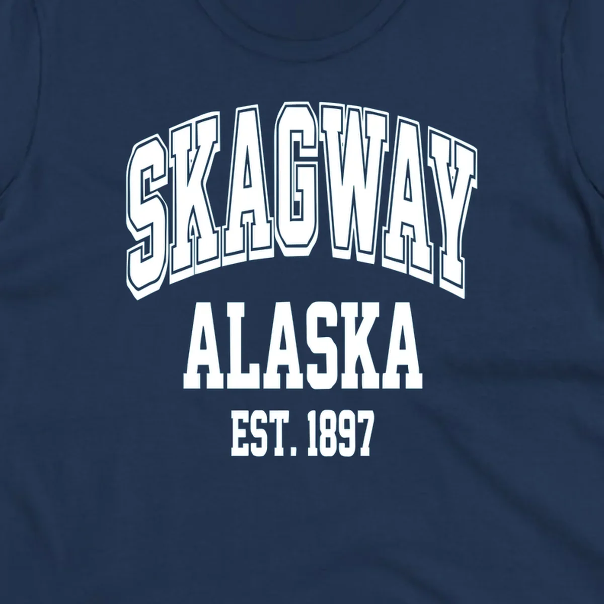 Vintage-style badge with bold outlined text reading Skagway Alaska Est. 1897 with decorative arrow accents on gray background.