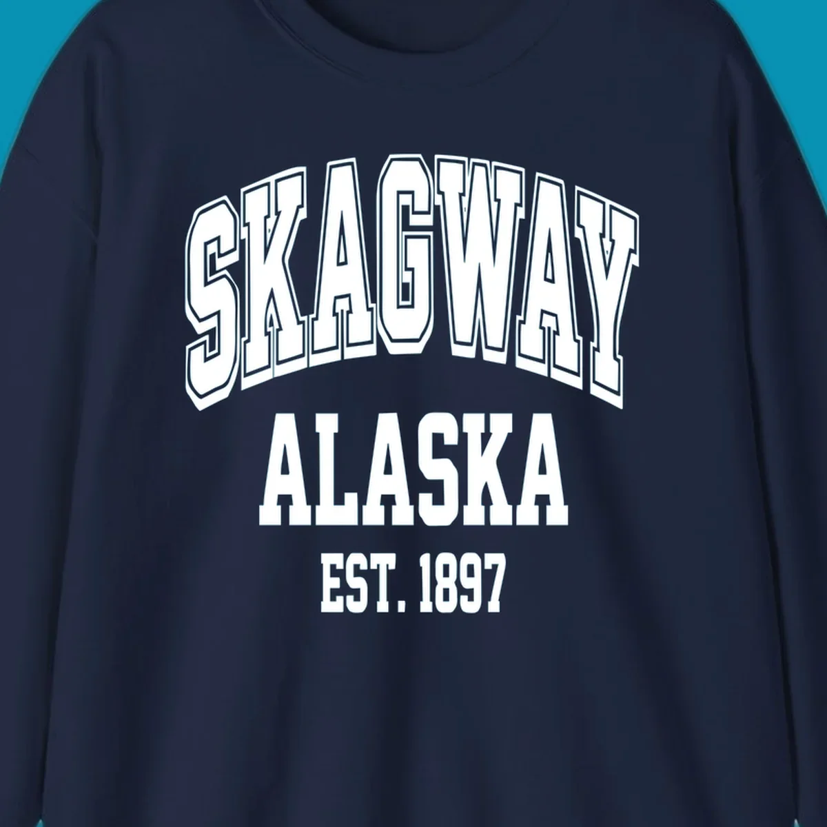 Vintage-style badge with bold outlined text reading Skagway Alaska Est. 1897 with decorative arrow accents on gray background.