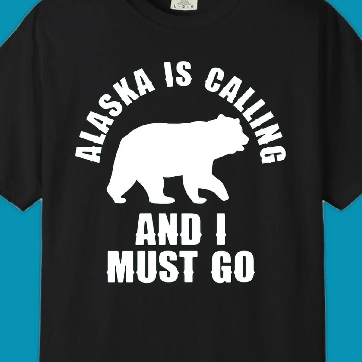 White bear silhouette with curved text reading 'Alaska is calling and I must go' on gray background