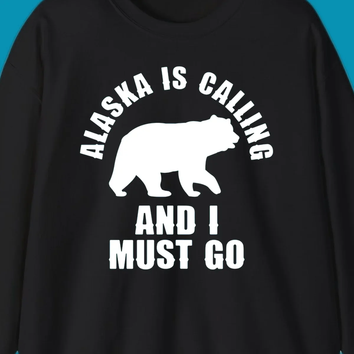 White bear silhouette with curved text reading 'Alaska is calling and I must go' on gray background