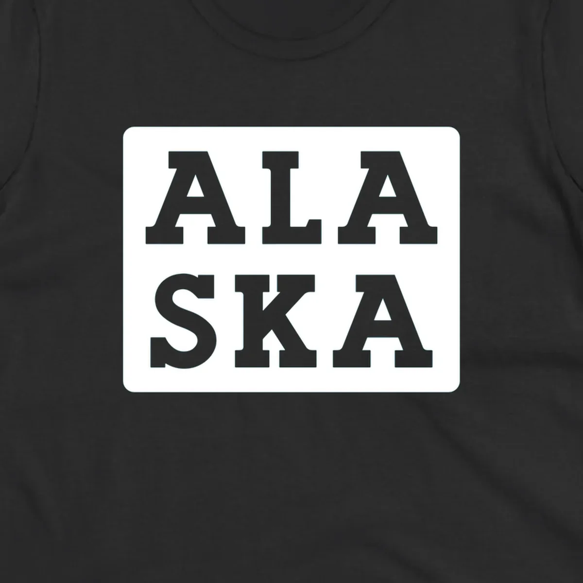 Bold gray block letters spelling 'ALA SKA' with geometric triangle cutouts, creating a playful Alaska pun design
