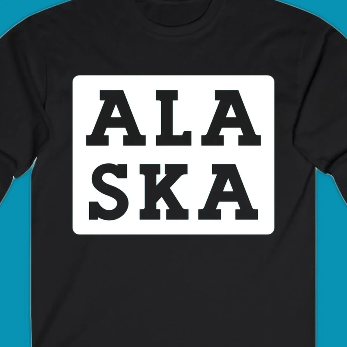 Bold gray block letters spelling 'ALA SKA' with geometric triangle cutouts, creating a playful Alaska pun design