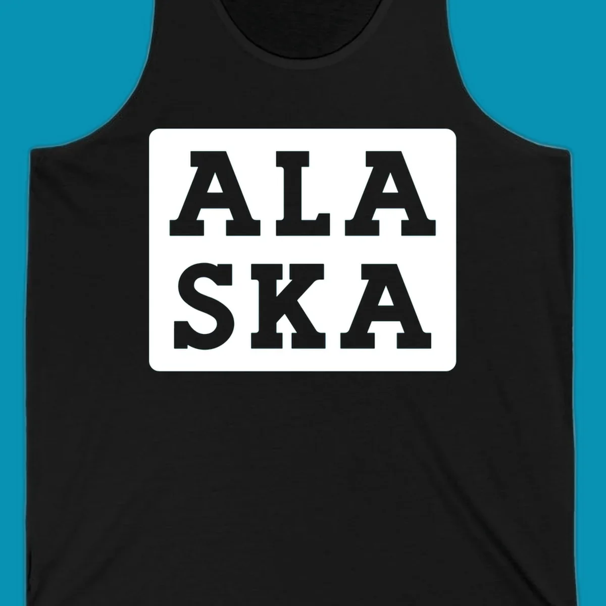 Bold gray block letters spelling 'ALA SKA' with geometric triangle cutouts, creating a playful Alaska pun design