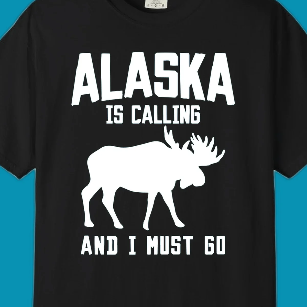White moose silhouette with text 'Alaska Is Calling And I Must Go' on gray background—Alaska is calling moose design