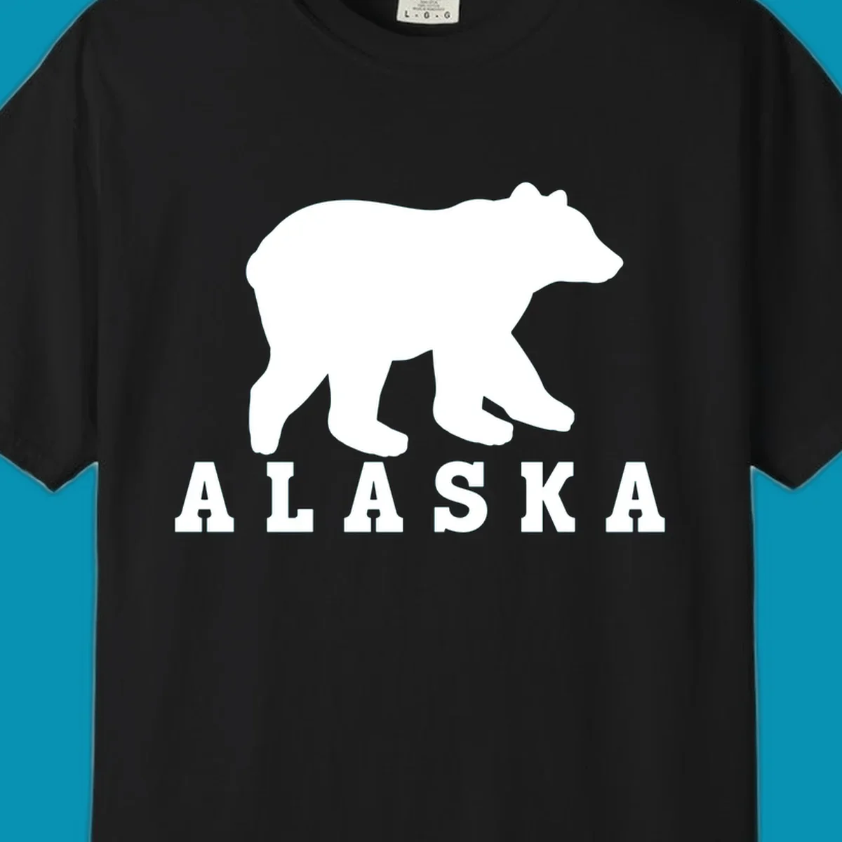 White bear silhouette standing with front paws visible, Alaska text below with pine tree accents on gray background