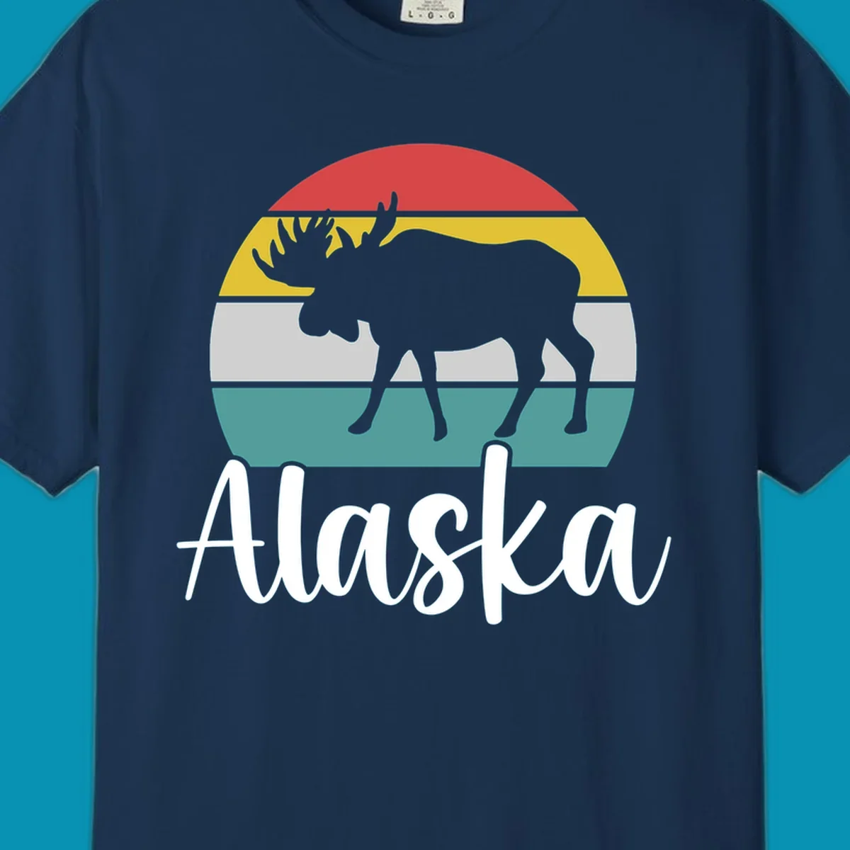 White moose silhouette against red, gold, gray, and teal horizontal stripes in a circular badge design representing Alaska mountains and wildlife.