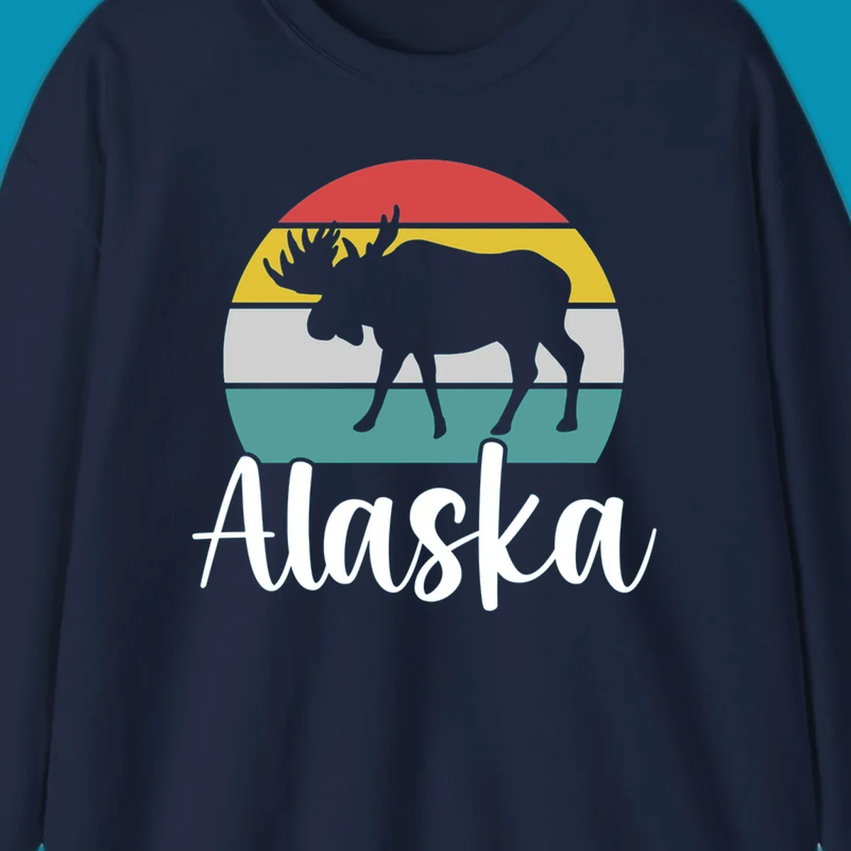 White moose silhouette against red, gold, gray, and teal horizontal stripes in a circular badge design representing Alaska mountains and wildlife.