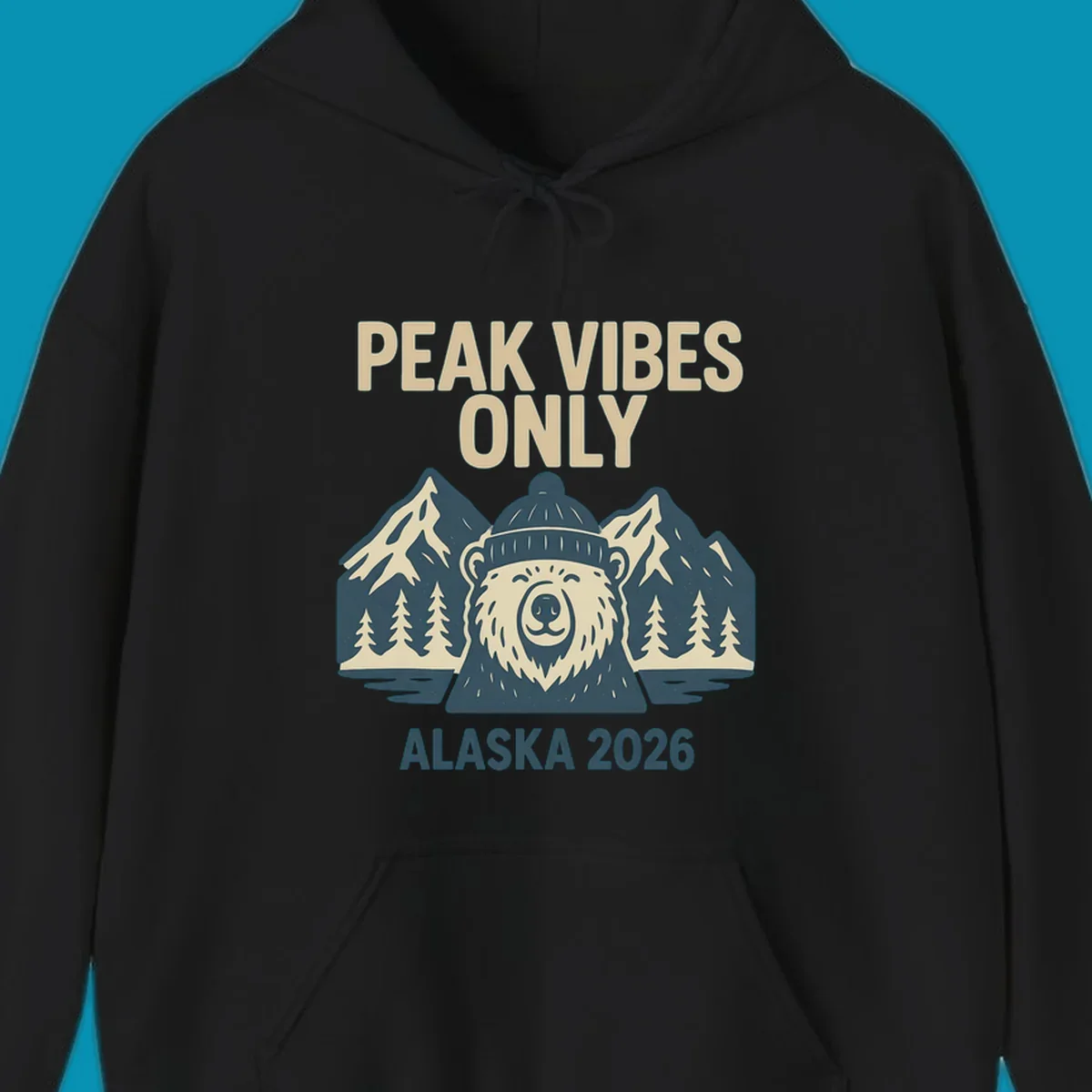 Vintage badge-style illustration of a smiling bear wearing a beanie with snow-capped mountains, evergreen trees, and water, text reads Peak Vibes Only Alaska 2026