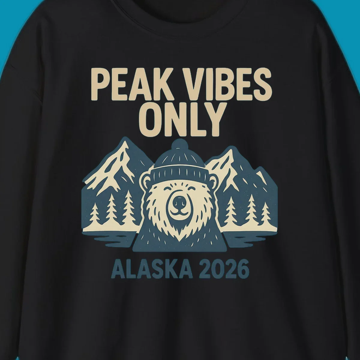 Vintage badge-style illustration of a smiling bear wearing a beanie with snow-capped mountains, evergreen trees, and water, text reads Peak Vibes Only Alaska 2026