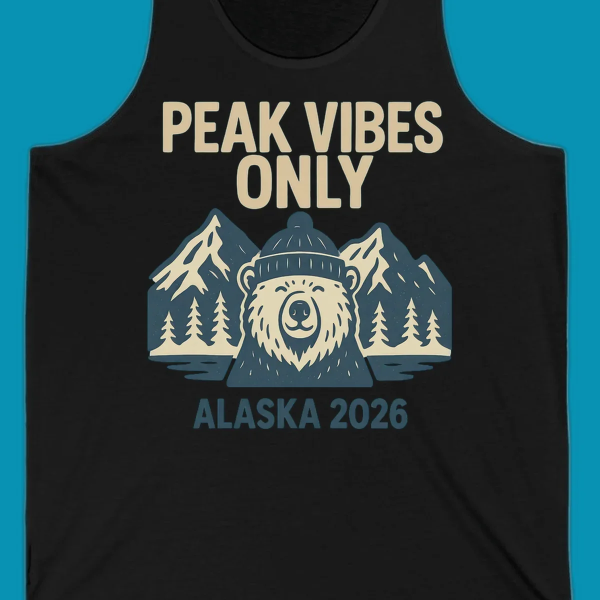 Vintage badge-style illustration of a smiling bear wearing a beanie with snow-capped mountains, evergreen trees, and water, text reads Peak Vibes Only Alaska 2026