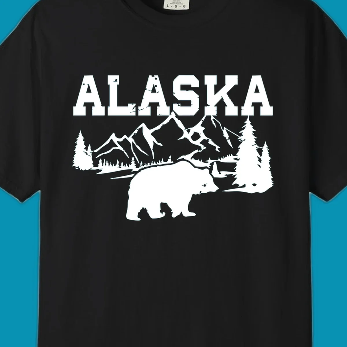 White silhouette illustration of a bear with mountains, evergreen trees, and river landscape under Alaska text on gray background