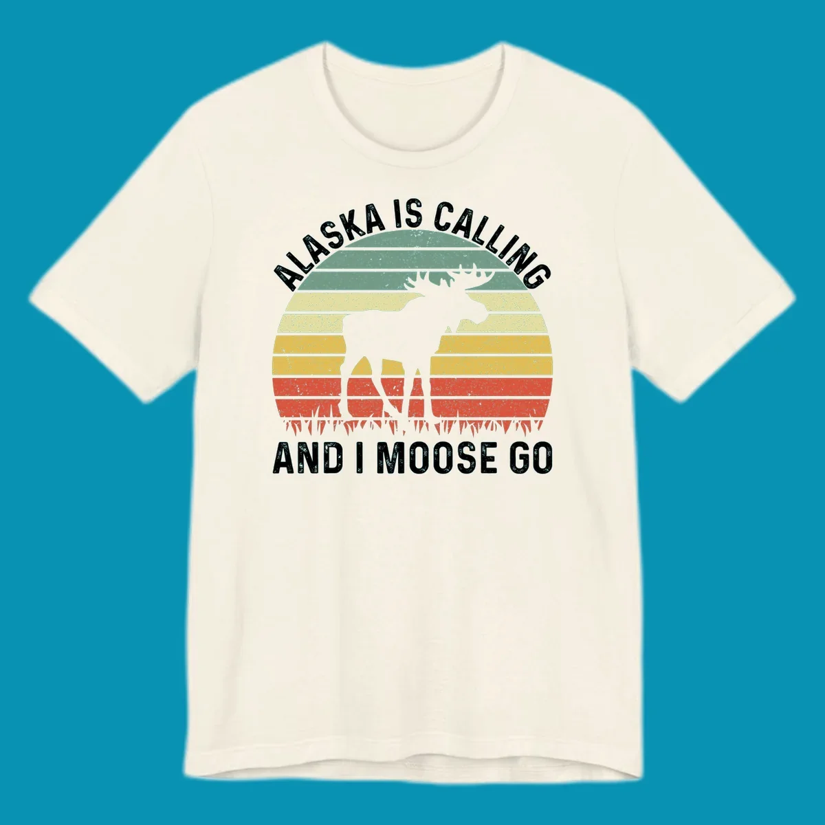 Distressed Alaska calling moose go design with moose and fish silhouettes against striped landscape layers in teal, yellow, and red