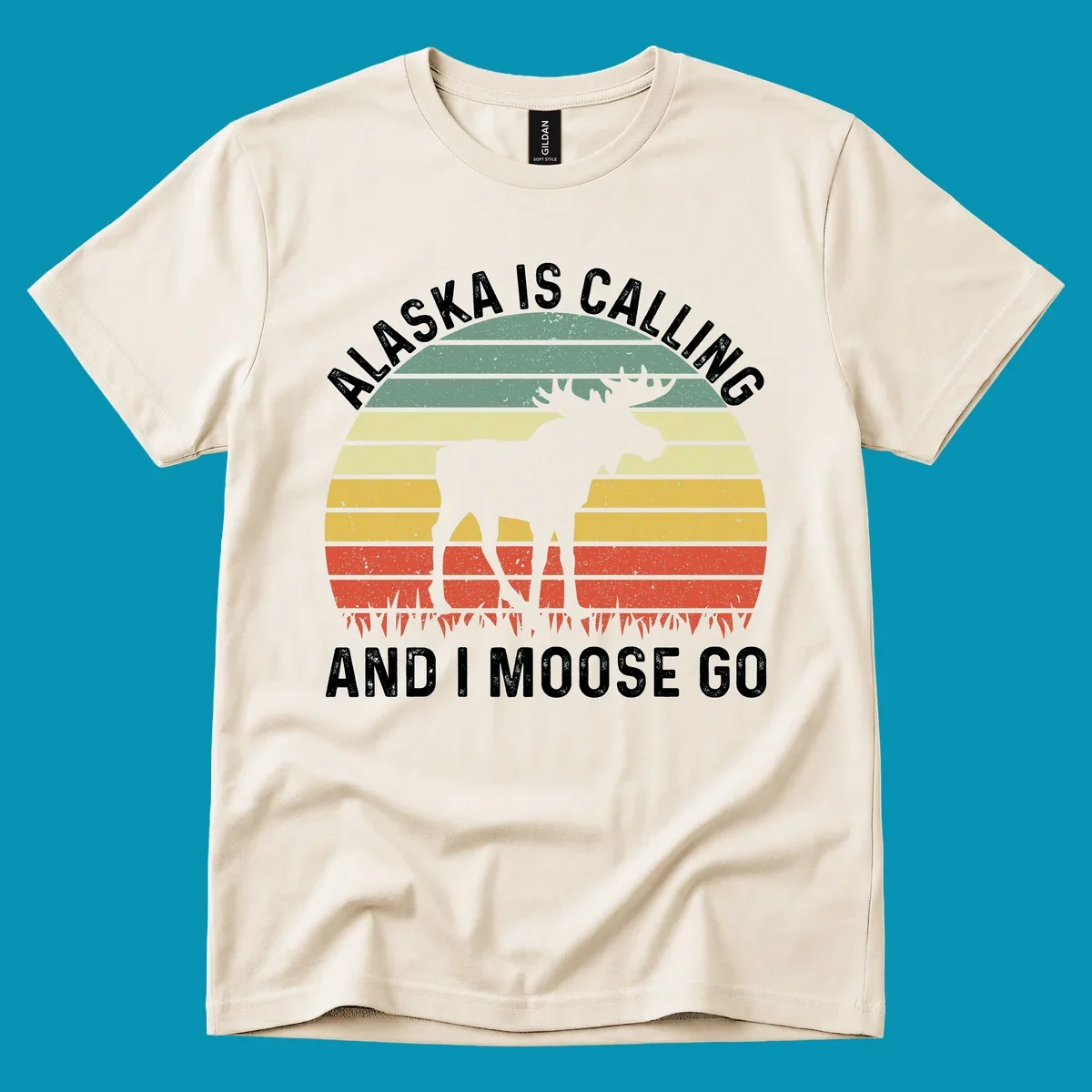 Distressed Alaska calling moose go design with moose and fish silhouettes against striped landscape layers in teal, yellow, and red
