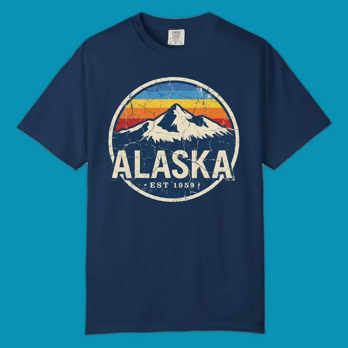 Vintage circular badge with snow-capped Alaska mountain, retro rainbow stripes, and distressed cream border featuring 'ALASKA EST 1959' text
