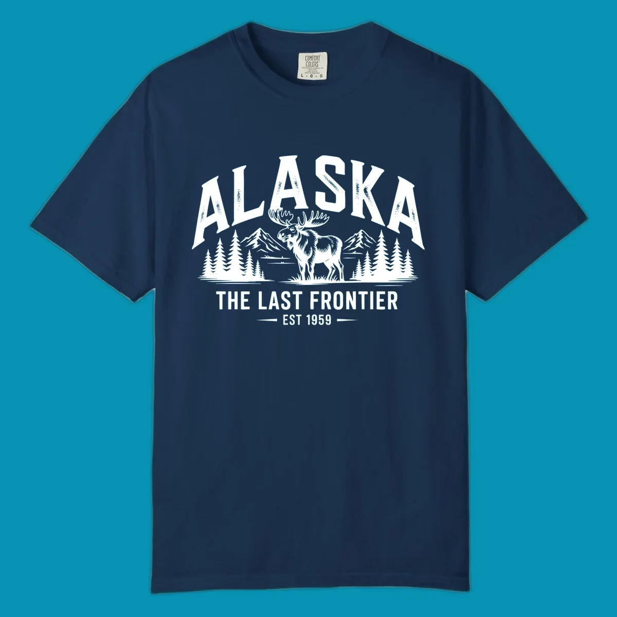 A white alaska-moose-frontier-scenic graphic showing a moose standing in front of mountains and pine trees.