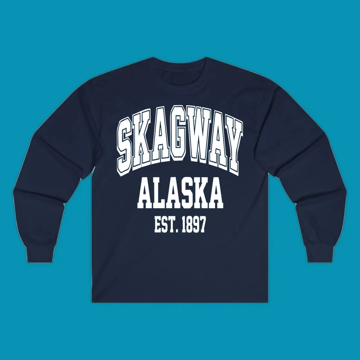 Vintage-style badge with bold outlined text reading Skagway Alaska Est. 1897 with decorative arrow accents on gray background.