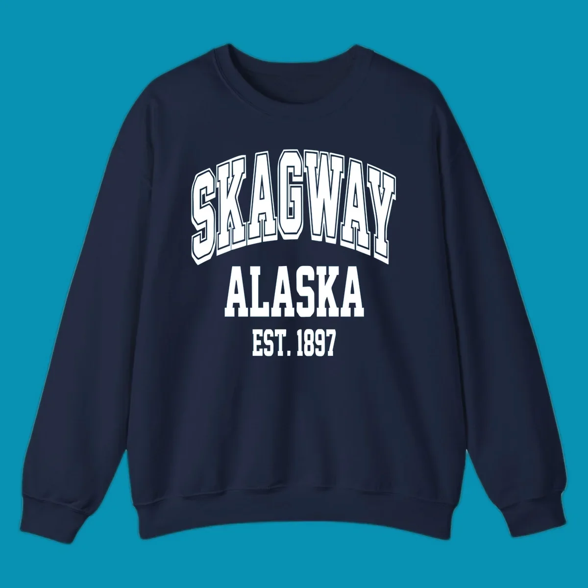 Vintage-style badge with bold outlined text reading Skagway Alaska Est. 1897 with decorative arrow accents on gray background.