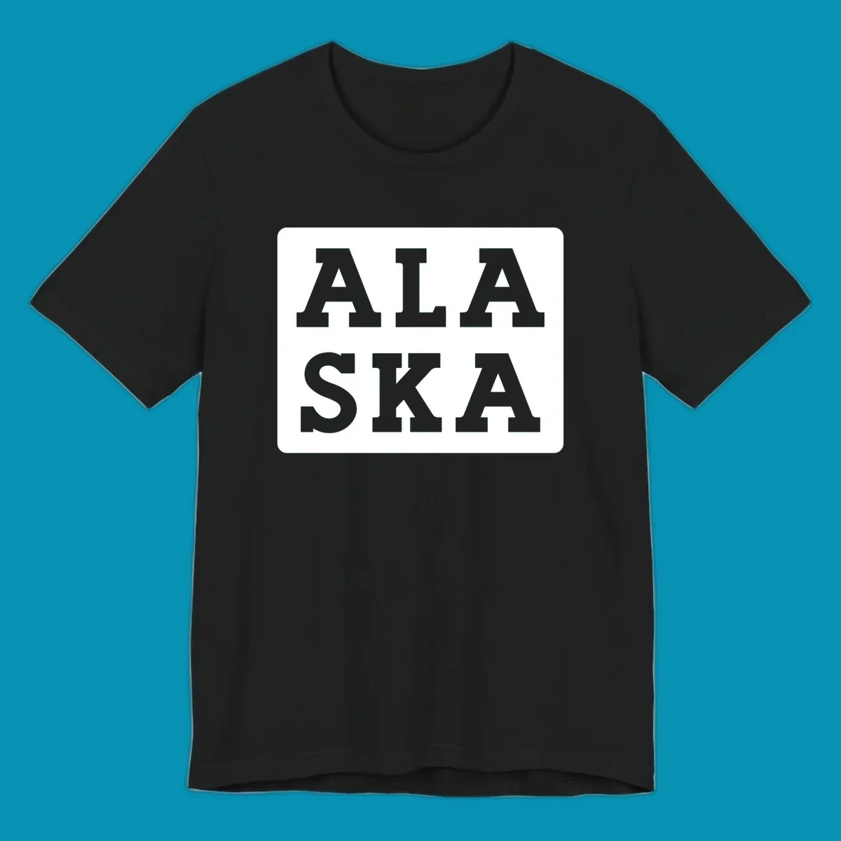 Bold gray block letters spelling 'ALA SKA' with geometric triangle cutouts, creating a playful Alaska pun design