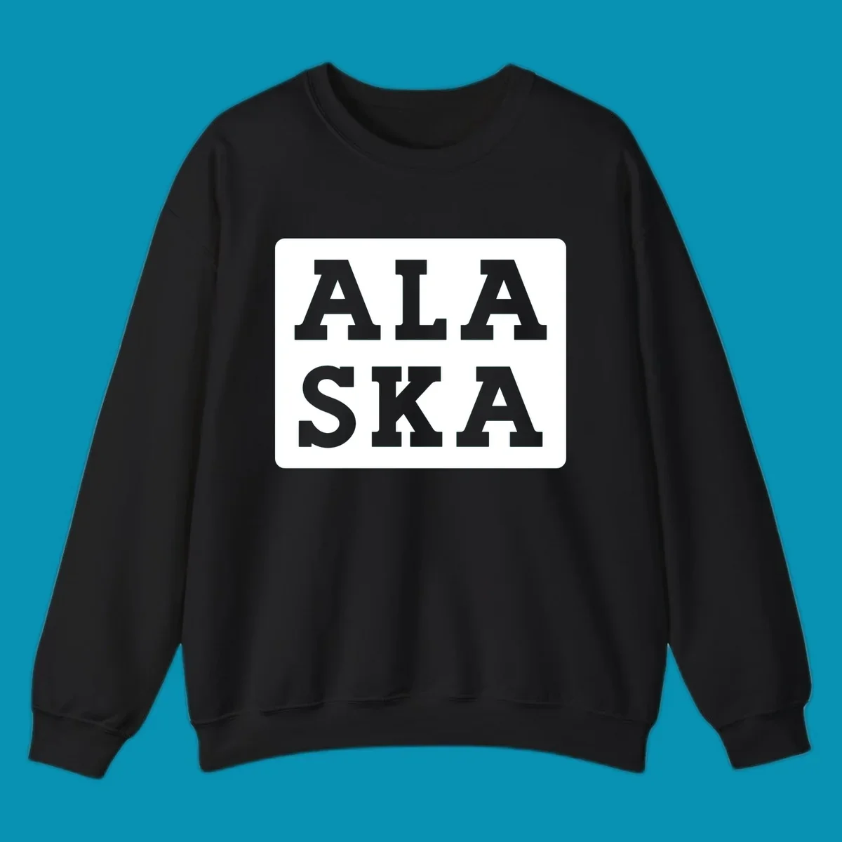 Bold gray block letters spelling 'ALA SKA' with geometric triangle cutouts, creating a playful Alaska pun design