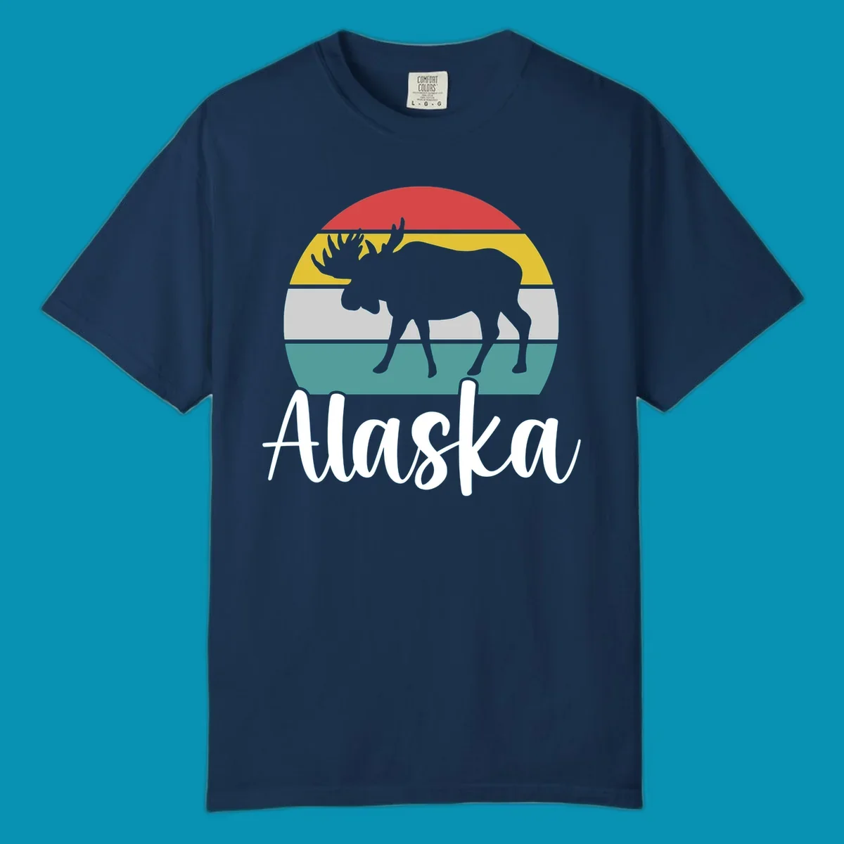 White moose silhouette against red, gold, gray, and teal horizontal stripes in a circular badge design representing Alaska mountains and wildlife.
