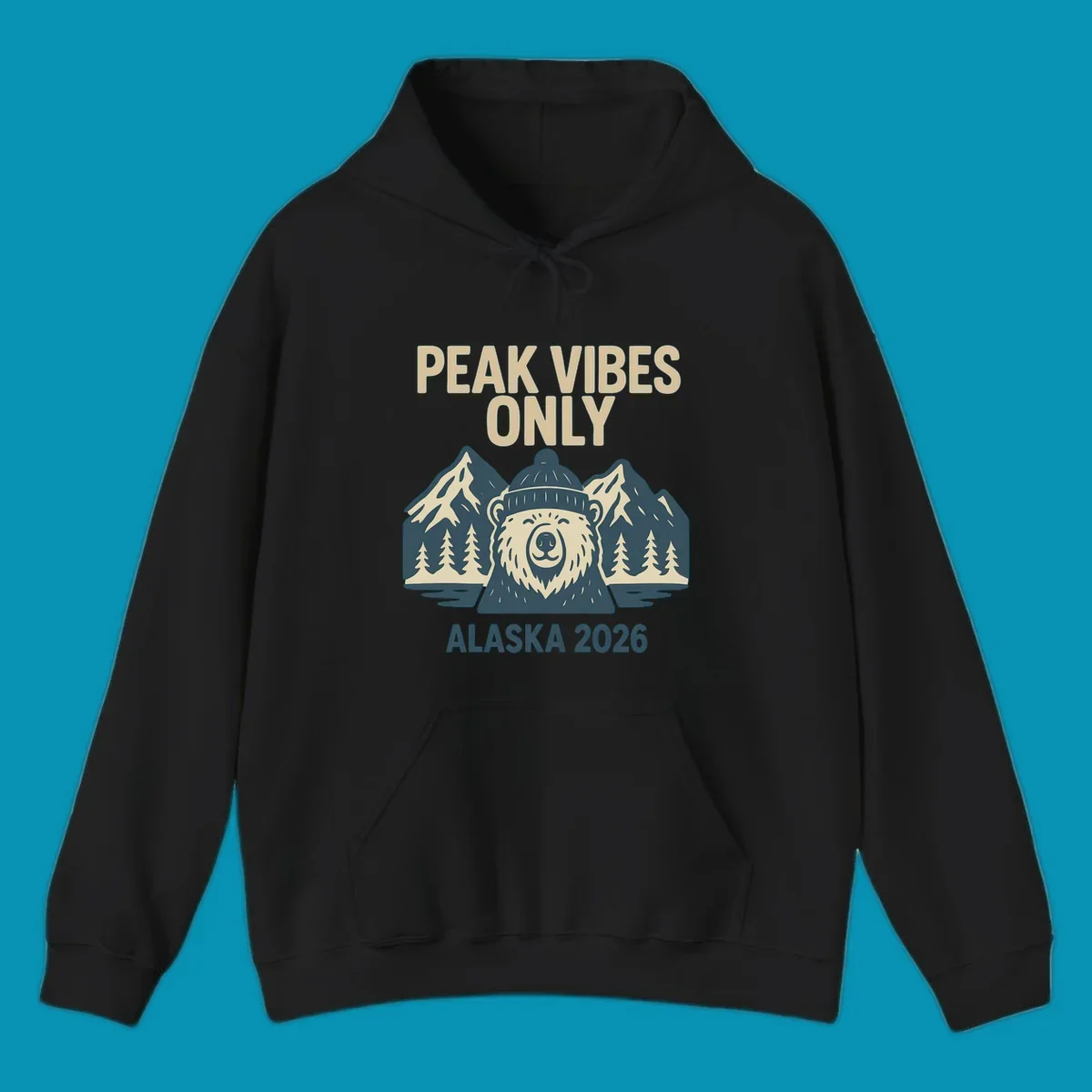 Vintage badge-style illustration of a smiling bear wearing a beanie with snow-capped mountains, evergreen trees, and water, text reads Peak Vibes Only Alaska 2026