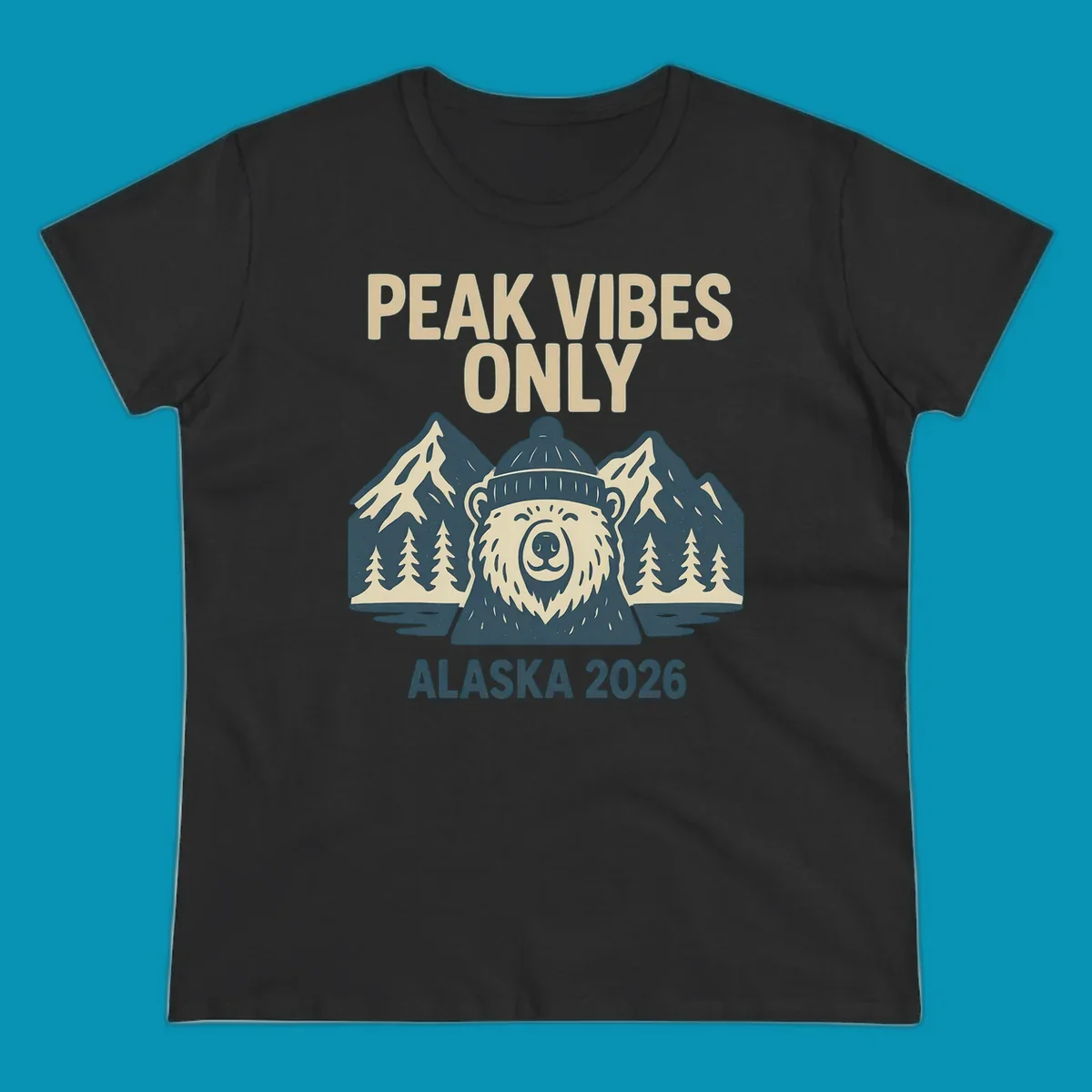 Vintage badge-style illustration of a smiling bear wearing a beanie with snow-capped mountains, evergreen trees, and water, text reads Peak Vibes Only Alaska 2026