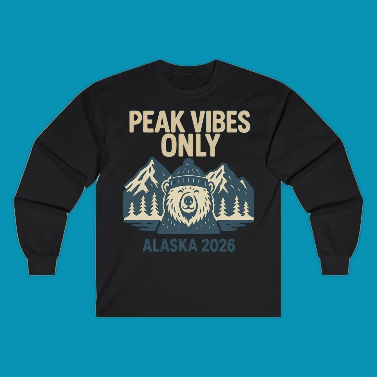 Vintage badge-style illustration of a smiling bear wearing a beanie with snow-capped mountains, evergreen trees, and water, text reads Peak Vibes Only Alaska 2026