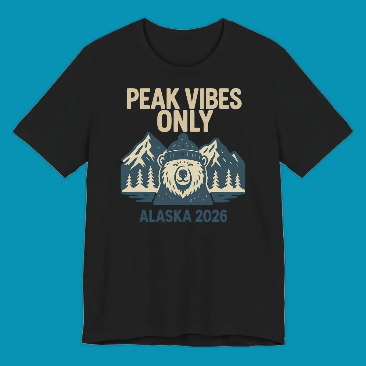 Vintage badge-style illustration of a smiling bear wearing a beanie with snow-capped mountains, evergreen trees, and water, text reads Peak Vibes Only Alaska 2026
