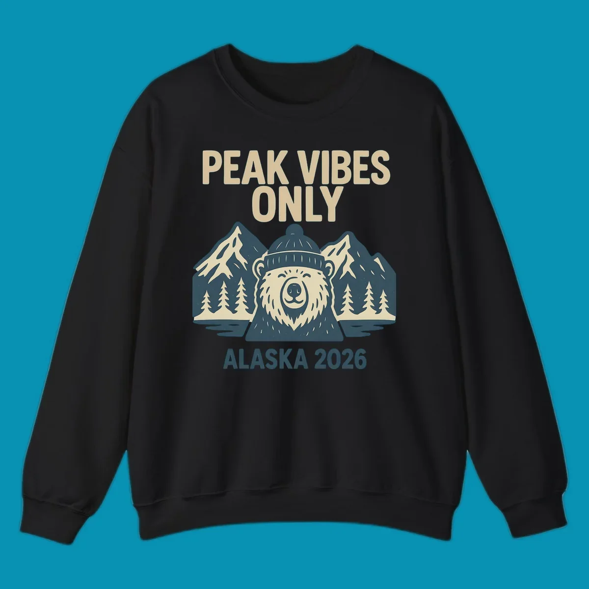 Vintage badge-style illustration of a smiling bear wearing a beanie with snow-capped mountains, evergreen trees, and water, text reads Peak Vibes Only Alaska 2026