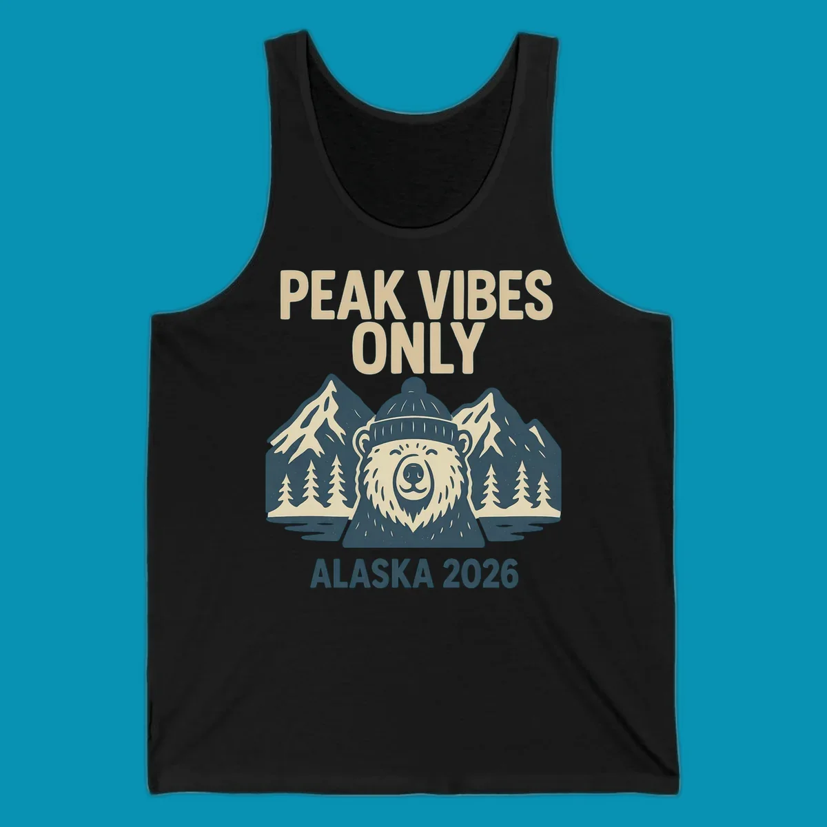 Vintage badge-style illustration of a smiling bear wearing a beanie with snow-capped mountains, evergreen trees, and water, text reads Peak Vibes Only Alaska 2026