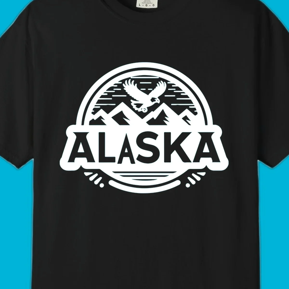 An oval badge design with a bald eagle flying above mountains and water, and the word ALASKA in bold text; alaska-eagle-mountain-badge.