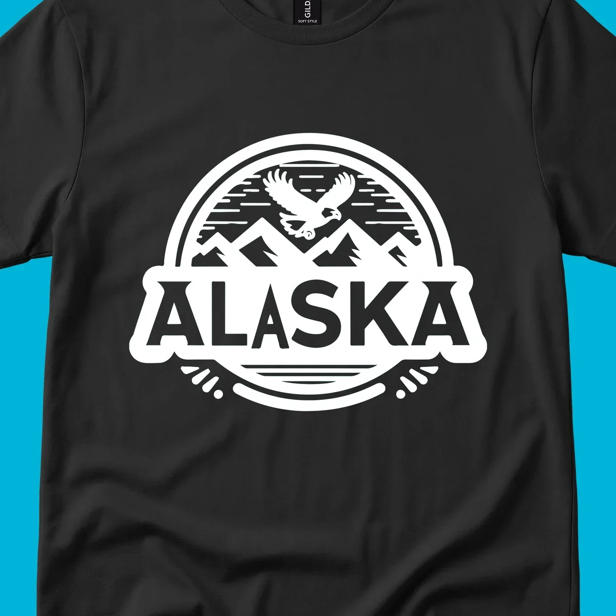 An oval badge design with a bald eagle flying above mountains and water, and the word ALASKA in bold text; alaska-eagle-mountain-badge.