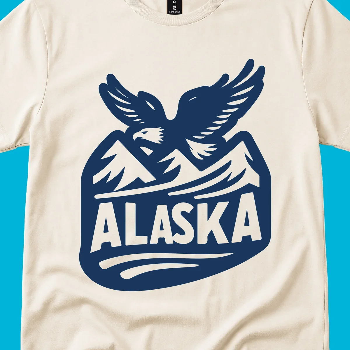 A white and dark blue badge design showing a flying eagle over mountain peaks with "ALASKA" text, for a cruise souvenir.
