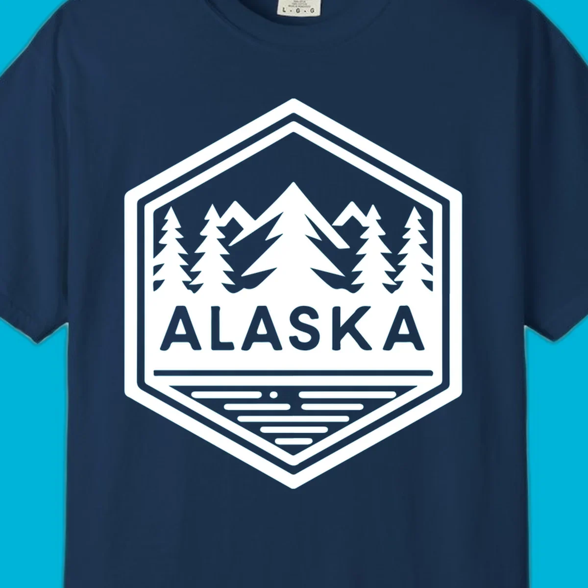 An Alaska mountain lake badge design in a hexagon shape, showing mountains, pine trees, and a lake below the ALASKA text.