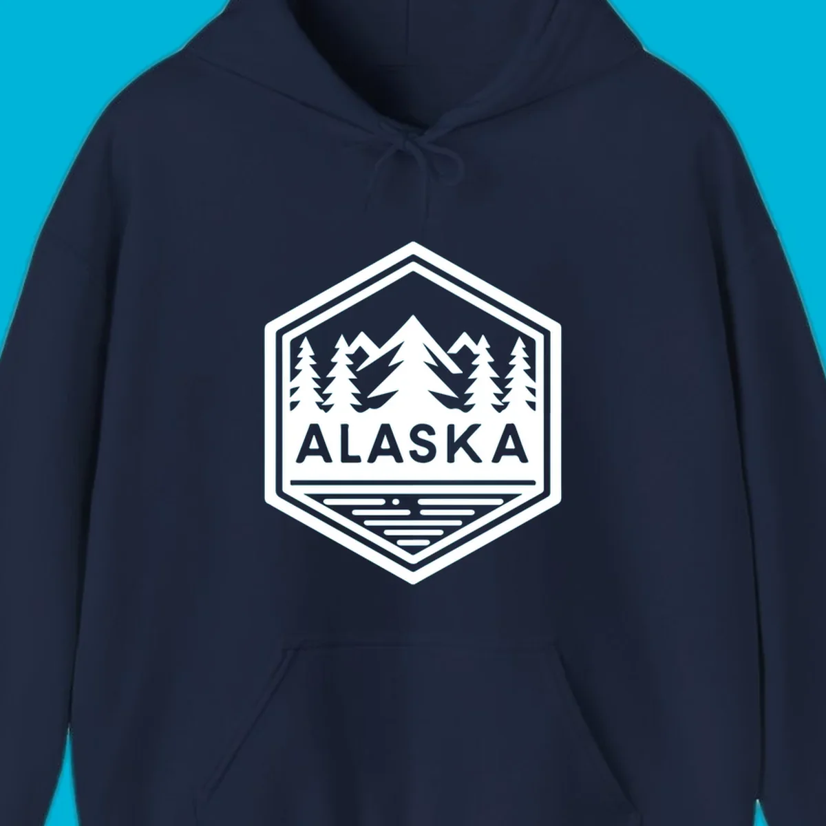 An Alaska mountain lake badge design in a hexagon shape, showing mountains, pine trees, and a lake below the ALASKA text.