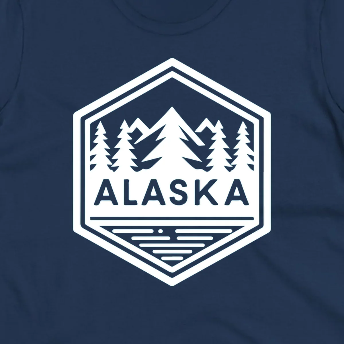 An Alaska mountain lake badge design in a hexagon shape, showing mountains, pine trees, and a lake below the ALASKA text.
