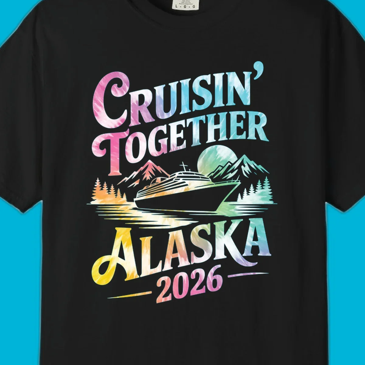 A tie-dye graphic featuring a cruise ship, mountains, and trees, with the text 'CRUISIN' TOGETHER ALASKA 2026'. This alaska-cruise-2026-tie-dye design shows a scenic view.