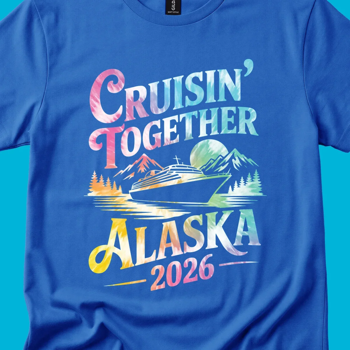 A tie-dye graphic featuring a cruise ship, mountains, and trees, with the text 'CRUISIN' TOGETHER ALASKA 2026'. This alaska-cruise-2026-tie-dye design shows a scenic view.