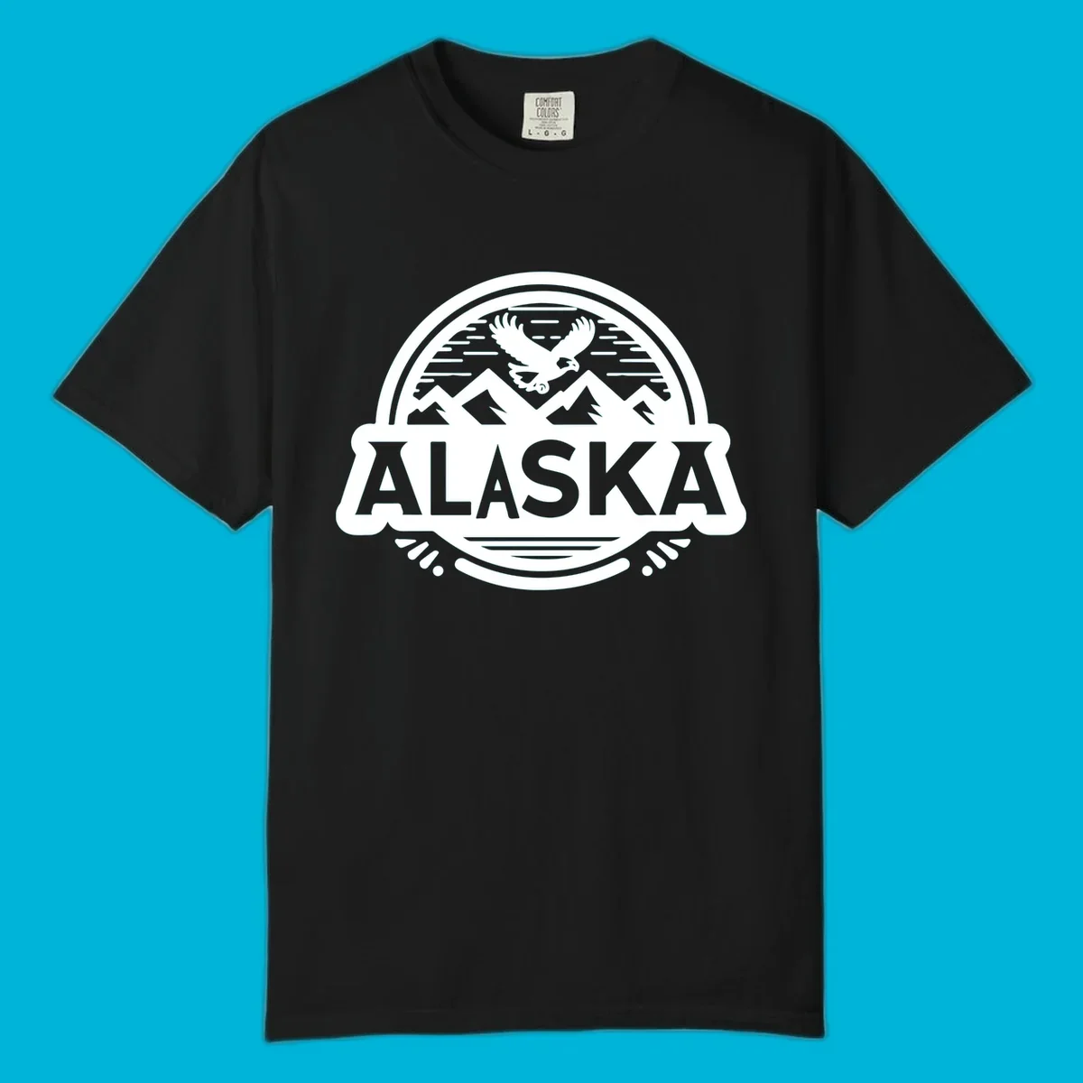 An oval badge design with a bald eagle flying above mountains and water, and the word ALASKA in bold text; alaska-eagle-mountain-badge.