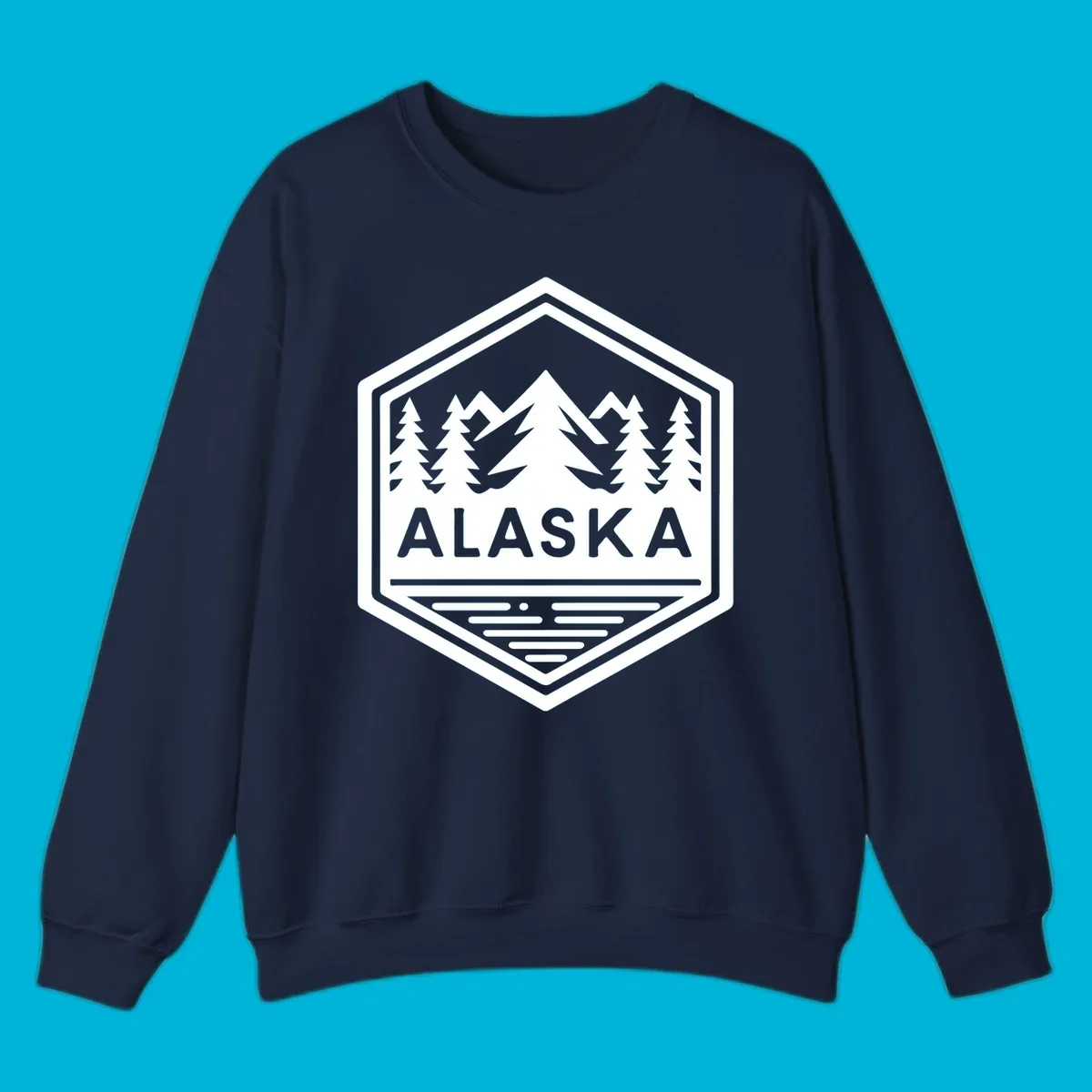 An Alaska mountain lake badge design in a hexagon shape, showing mountains, pine trees, and a lake below the ALASKA text.