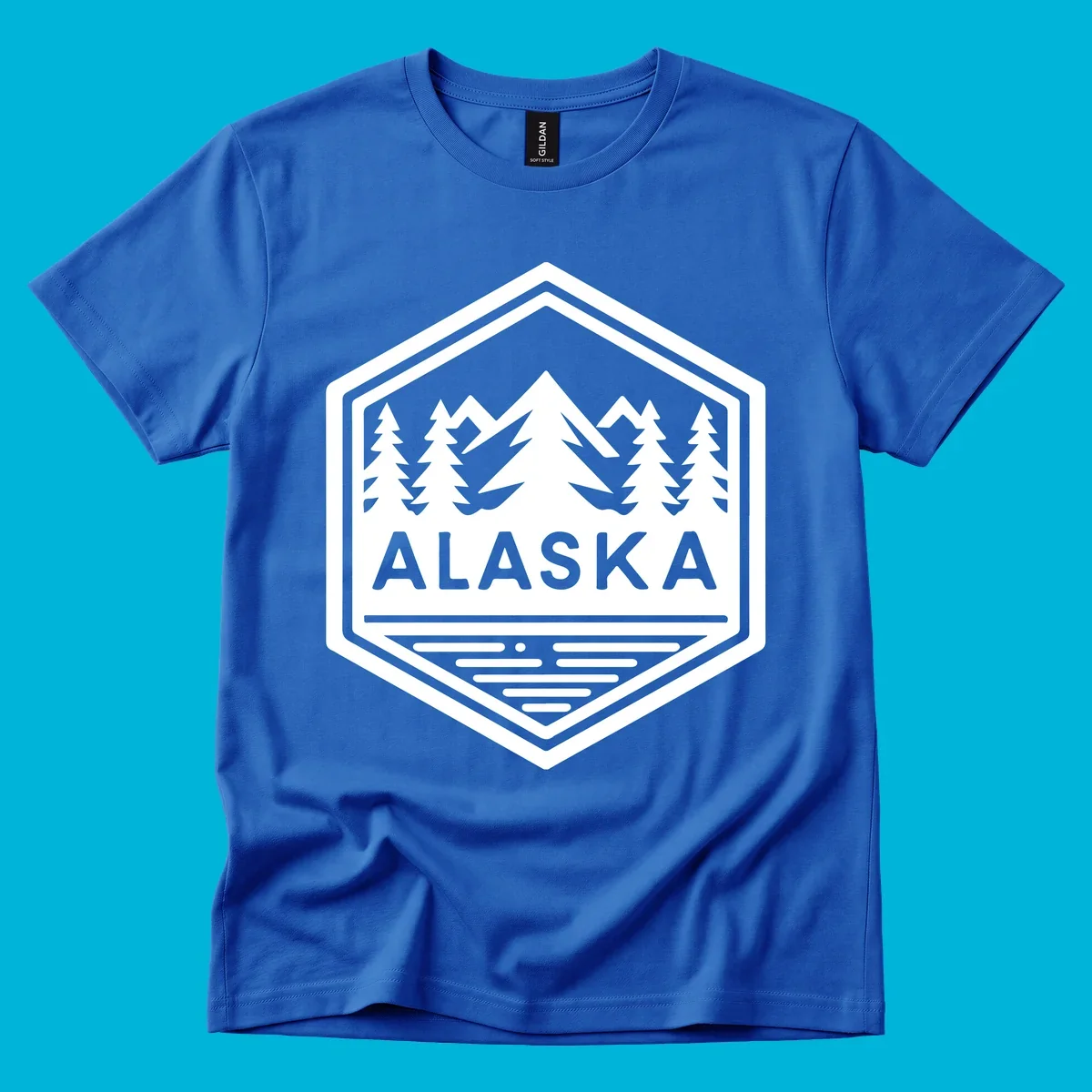 An Alaska mountain lake badge design in a hexagon shape, showing mountains, pine trees, and a lake below the ALASKA text.