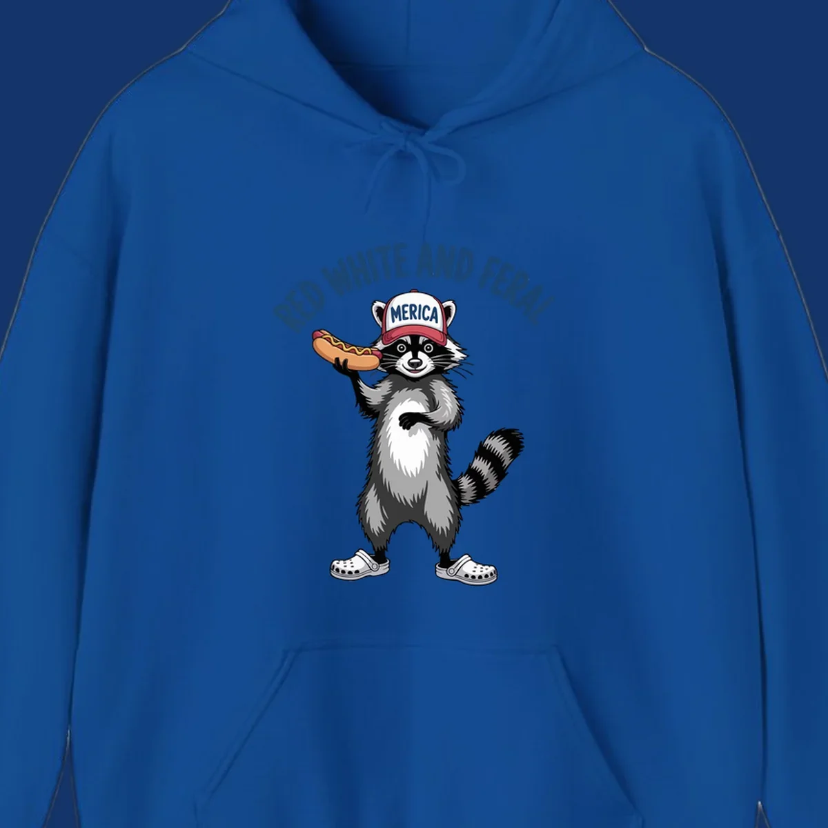 A patriotic raccoon in a MERICA hat and Crocs holds a hot dog, with 'RED WHITE AND FERAL' text. Features the red-white-feral-raccoon concept.