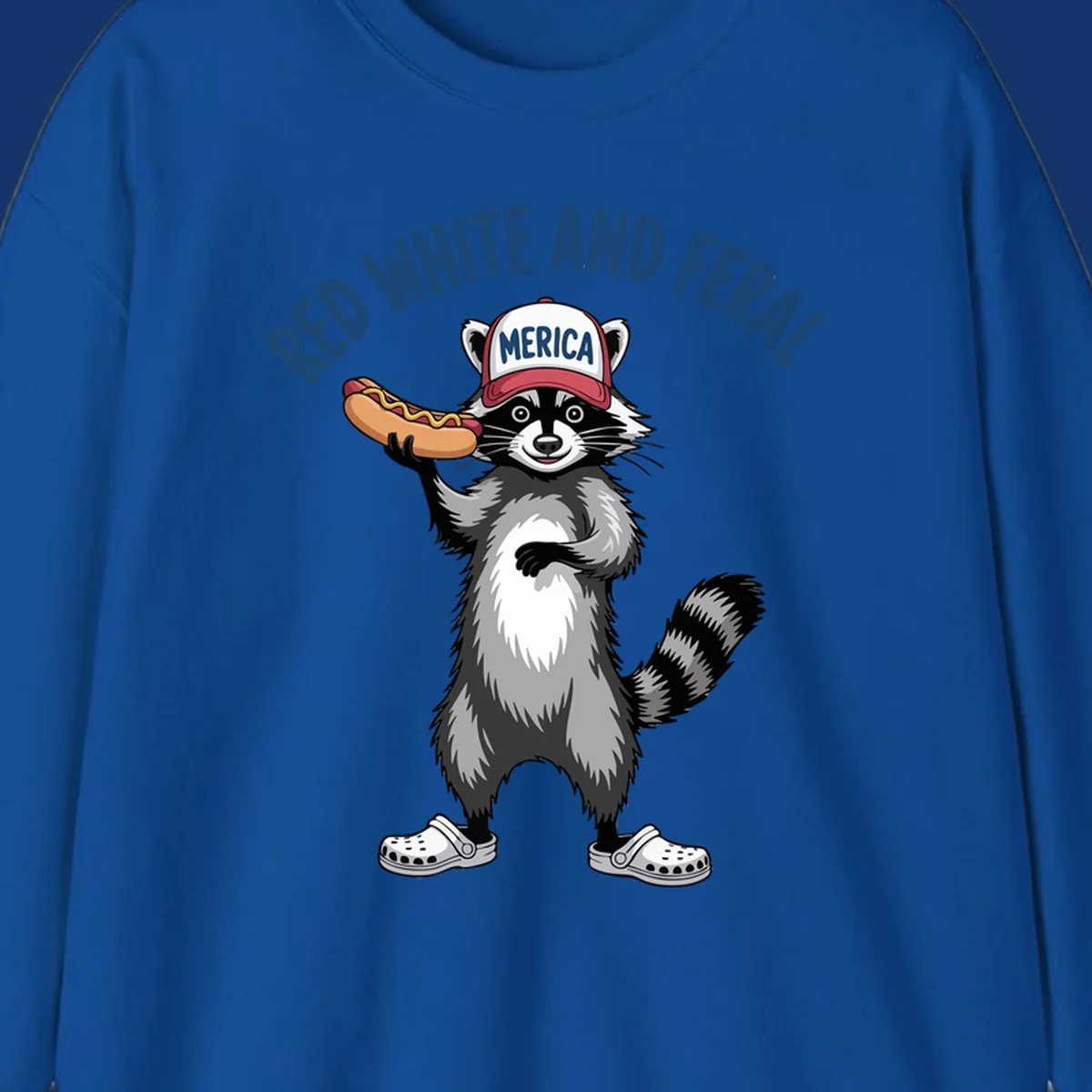 A patriotic raccoon in a MERICA hat and Crocs holds a hot dog, with 'RED WHITE AND FERAL' text. Features the red-white-feral-raccoon concept.