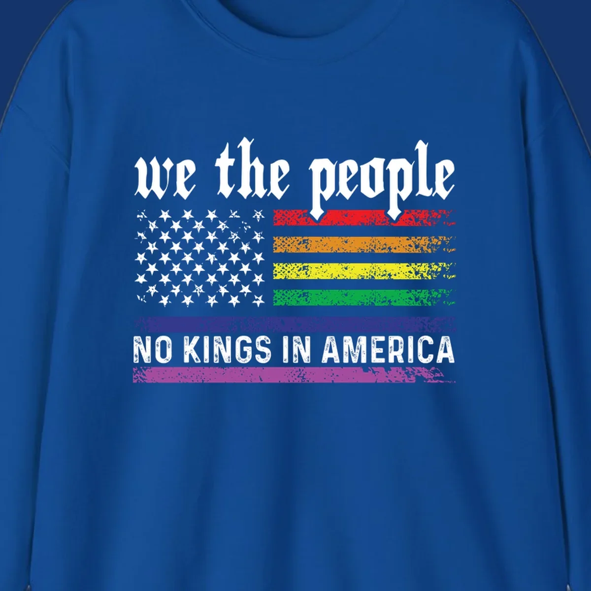 A distressed American flag with rainbow stripes and white stars, featuring 'we the people' and 'NO KINGS IN AMERICA' text.